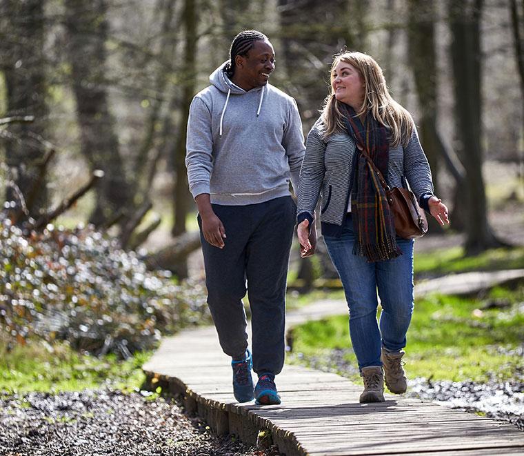 A man and a woman walking on a trail while talking, related to Global Obesity Research