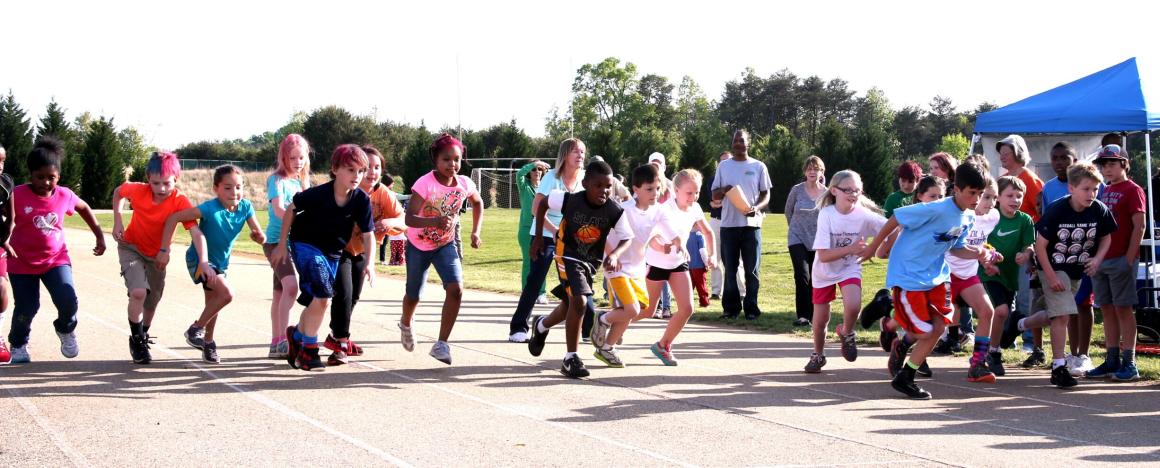 Children running on a playground, while parents watch from the side