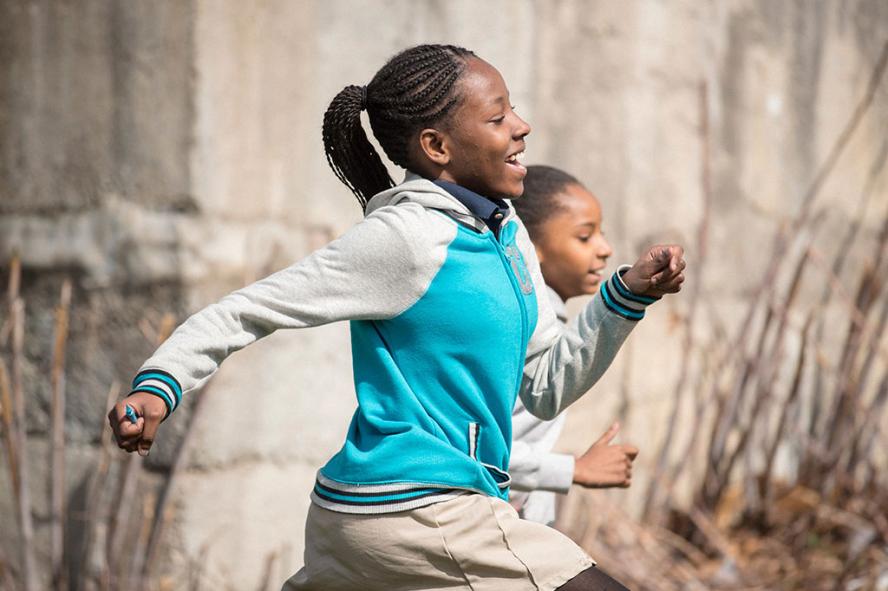 A girl in a blue jacket running while holding a blue pen