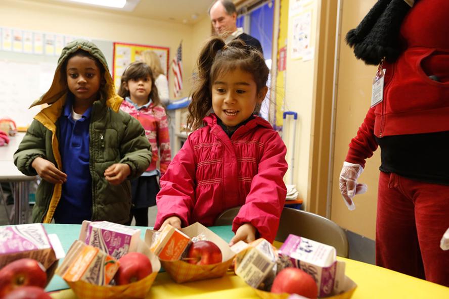 A girl picking up breakfast while other children wait in line