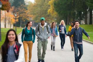 Students walking on a college campus, with one student talking on the phone, as part of the Evaluating the Healthier Campus Initiative