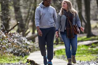 A man and a woman walking on a trail while talking, related to Global Obesity Research