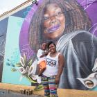 A mother holding her child while standing in front of a colorful mural